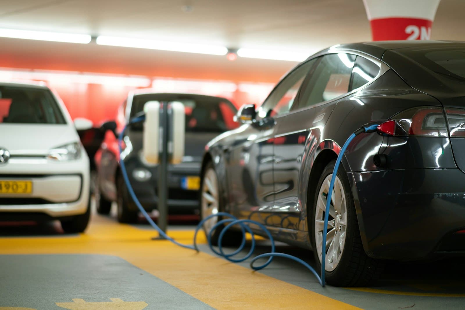 Electric vehicles charging side by side, cables connected to wall mounted chargers